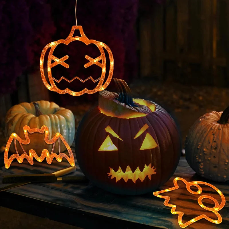 Orange pumpkin, bat and ghost LED decorations beside Halloween pumpkins