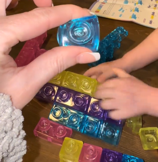 Hands joining blue jelly blocks to a small colorful build