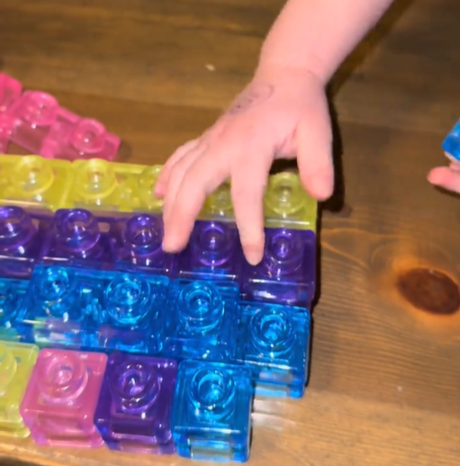 Hands stacking colorful jelly blocks on a table