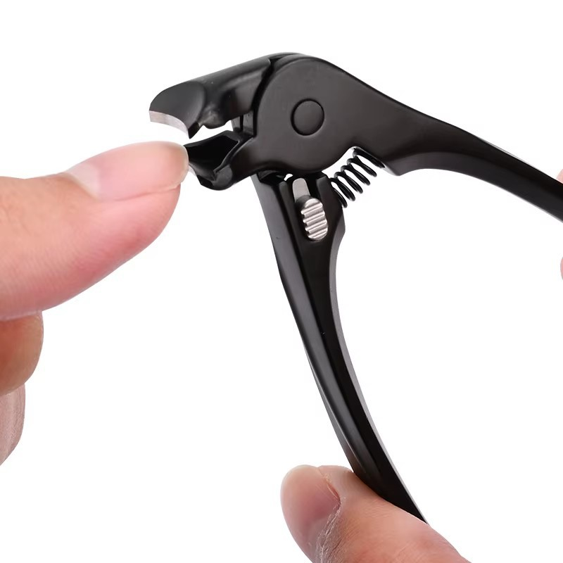 Black nail clipper held near a fingernail