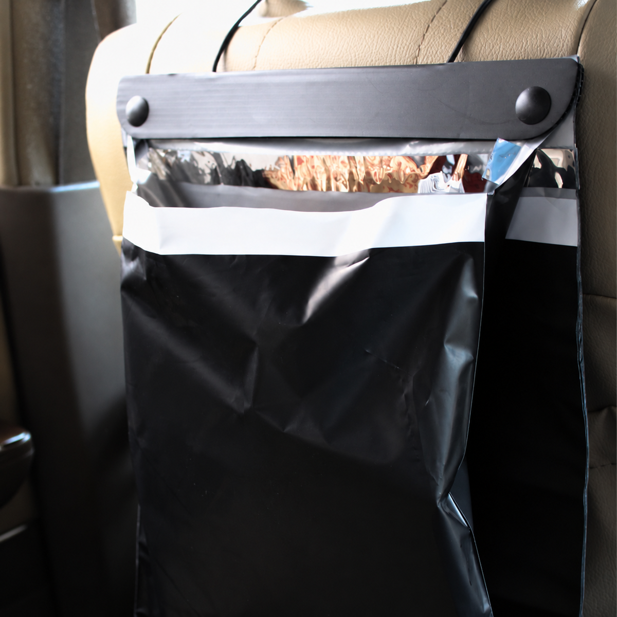 A filled black hanging car trash bag on a seat headrest
