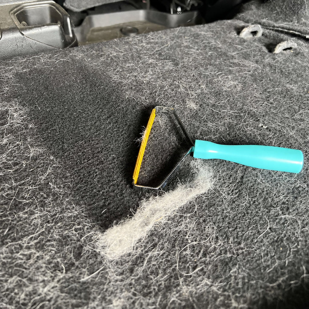Manual hair remover collecting pet fur from dark fabric